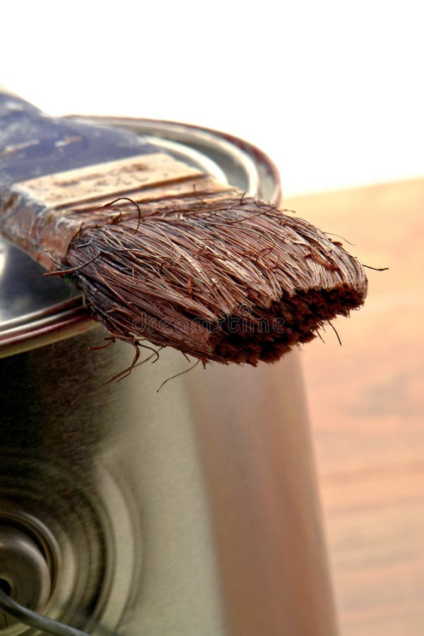 Dry Paint Brush on a Painting Mix Can. Bristle painting brush with dry brown color enamel resting on a paint can during a home painting renovation project royalty free stock images